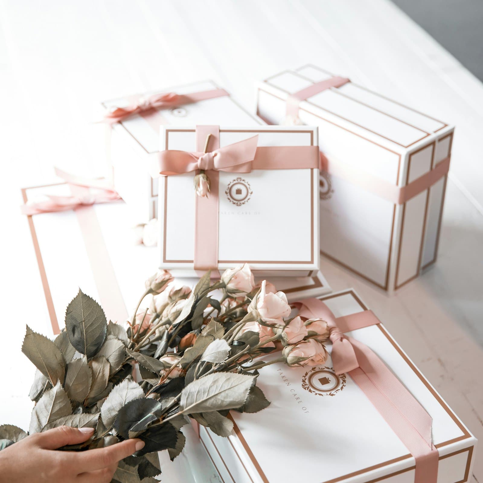 Coffrets cadeaux blancs noués de rubans roses, avec un bouquet de roses séchées