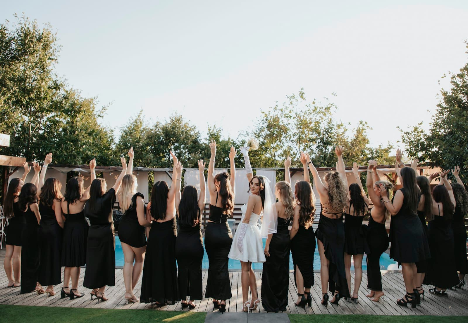 La mariée et ses amies célèbrent bras levés en plein air
