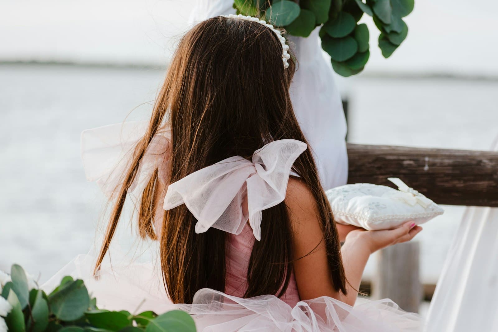Une fillette en robe rose porte le coussin des alliances