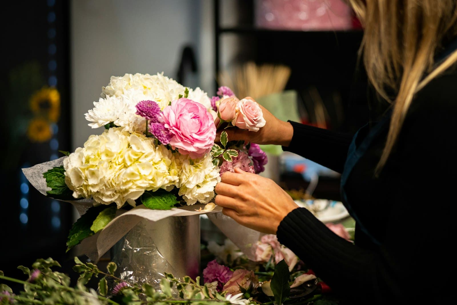 Une fleuriste compose un bouquet dans un vase