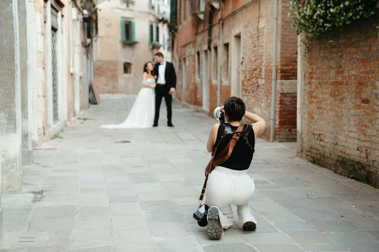 Un photographe photographie des mariés dans une ruelle