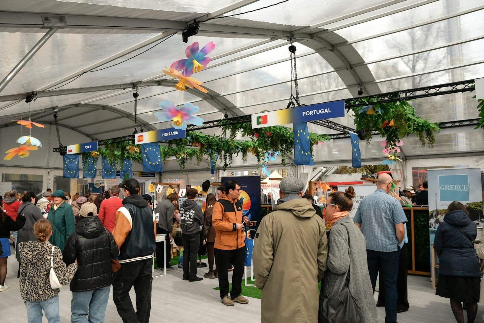 Visiteurs entre des stands décorés sous un grand chapiteau