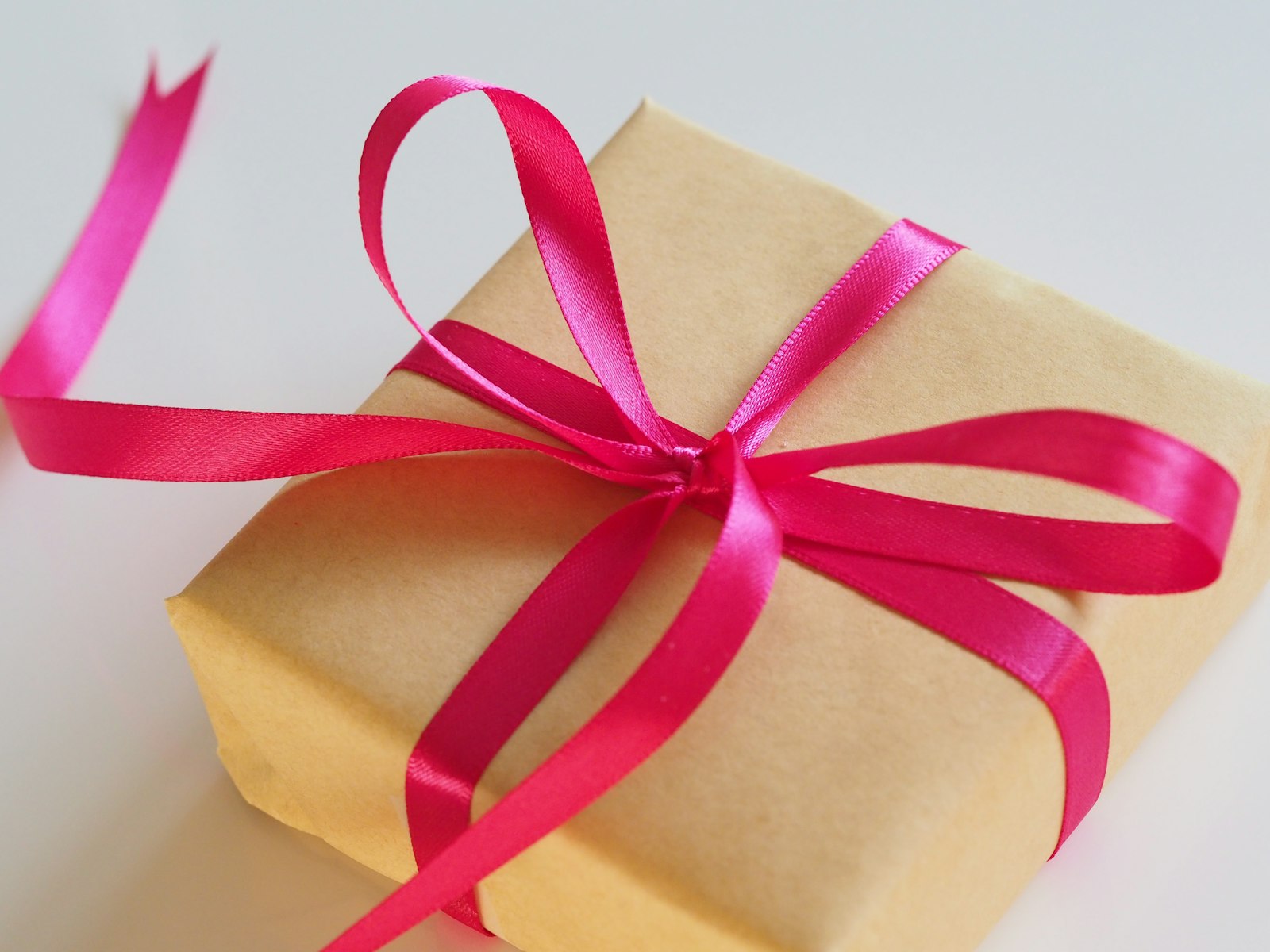Paquet cadeau en papier kraft noué d’un ruban rose