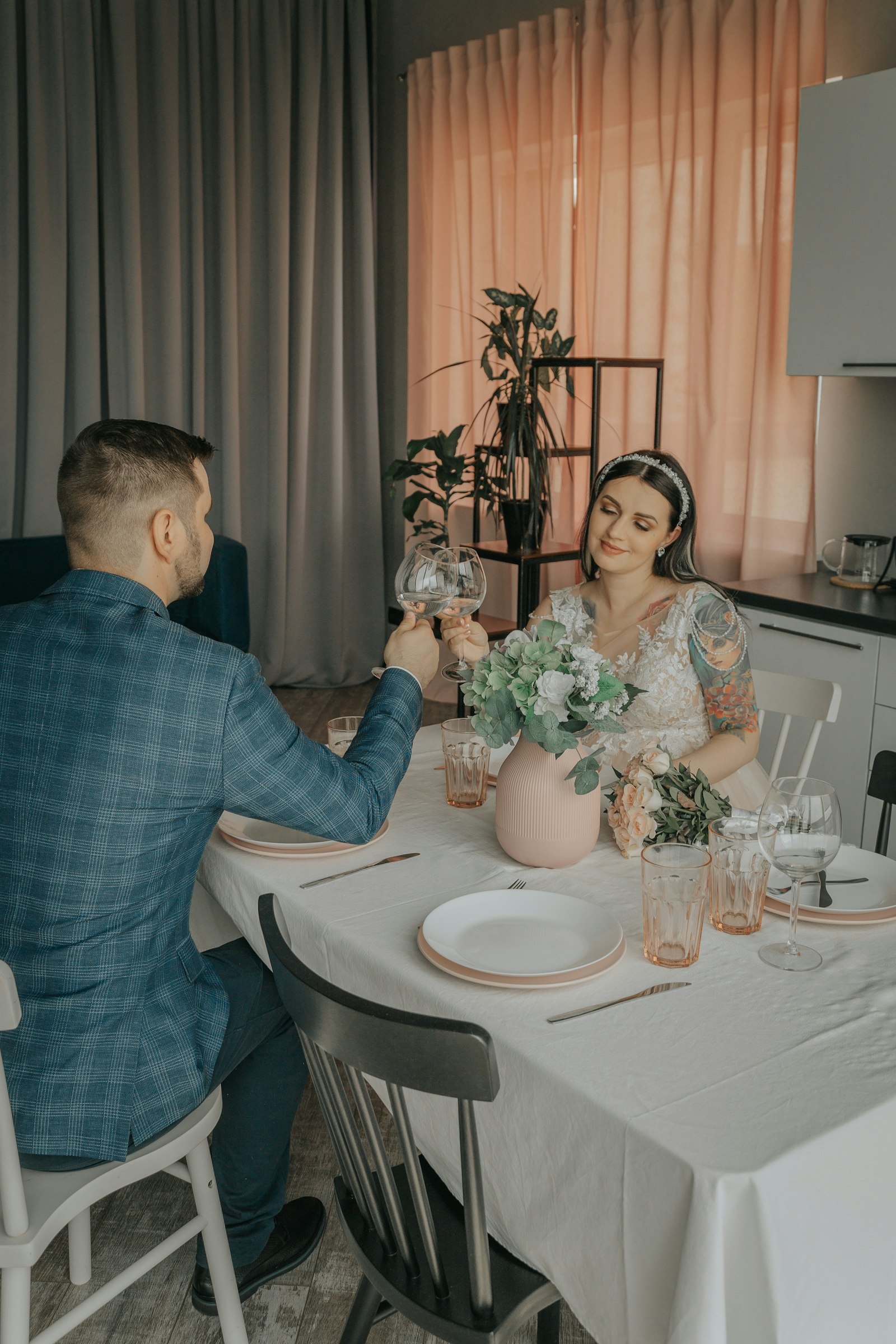 Jeunes mariés trinquant à une table dressée avec un bouquet de fleurs