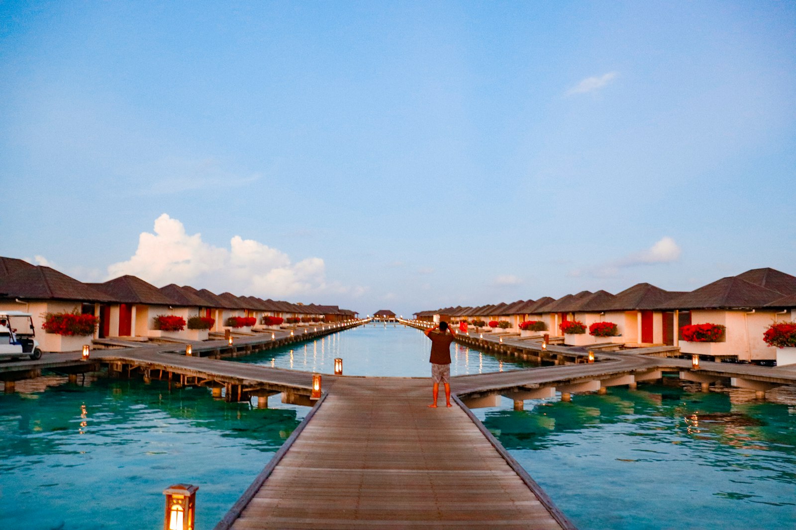 Ponton en bois menant à des bungalows sur pilotis au-dessus d’un lagon turquoise